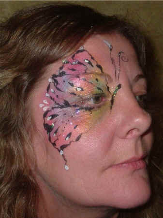 Face Painting: Adult female with pearlescent butterfly wing painted about her right eye.