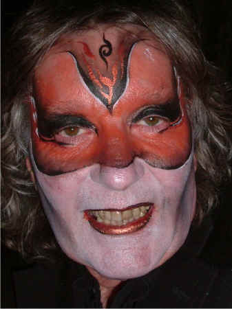 Face Painting: Adult male with painted mask in shades of bronze and highlighted in greys and black. Remainder of face in white base and representing the artists impression of the Phantom Of The Opera.
